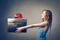 Frau mit Geschenk - Schenken hält die Beziehung jung?